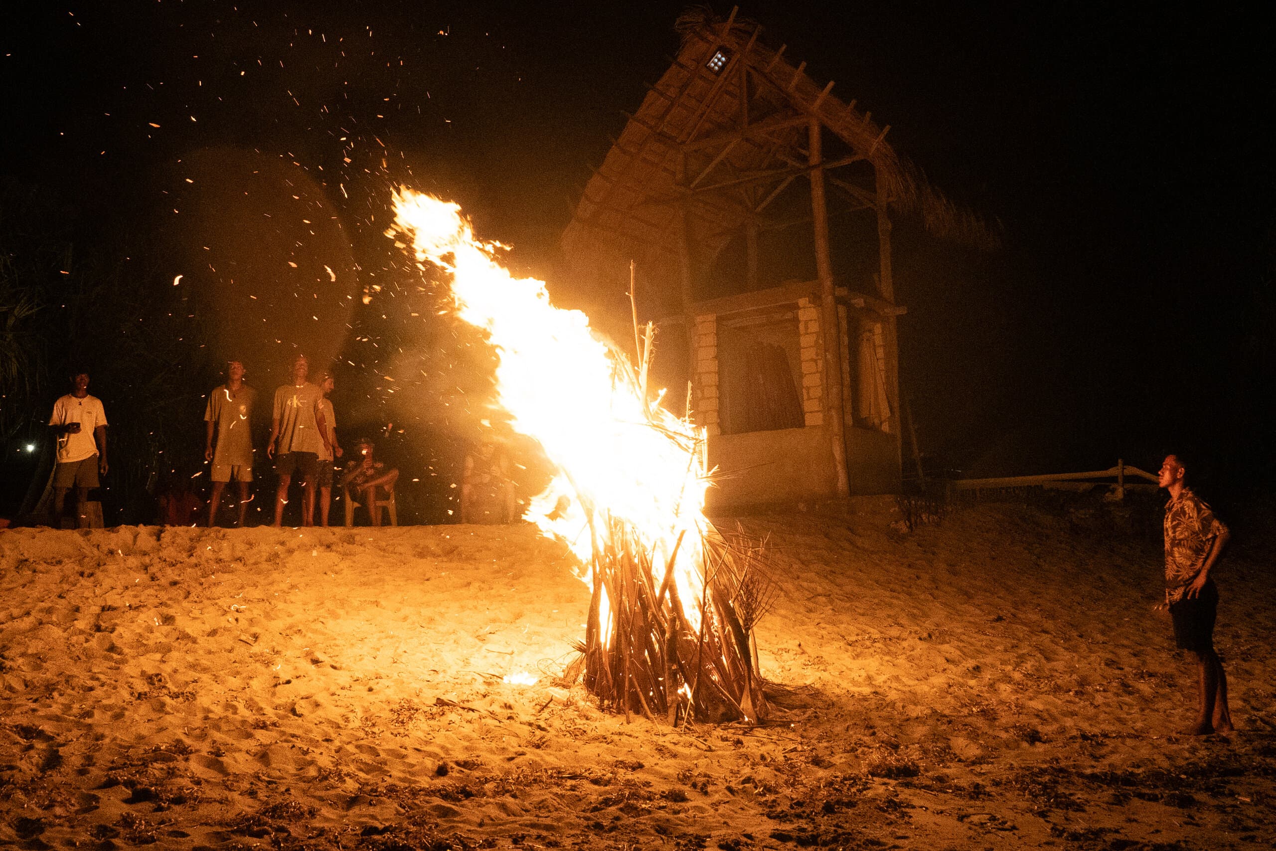 Tall beach bonfire flames lighting up the beach