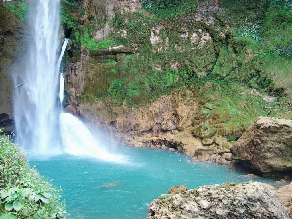 Matayangu waterfall with blue water and ancient banyan trees